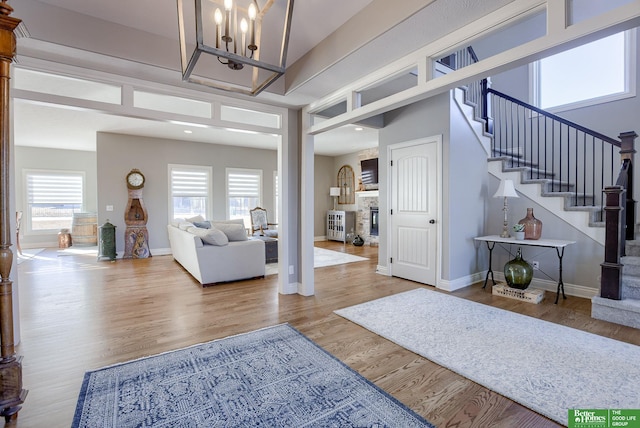 foyer entrance with stairway, baseboards, wood finished floors, and a chandelier