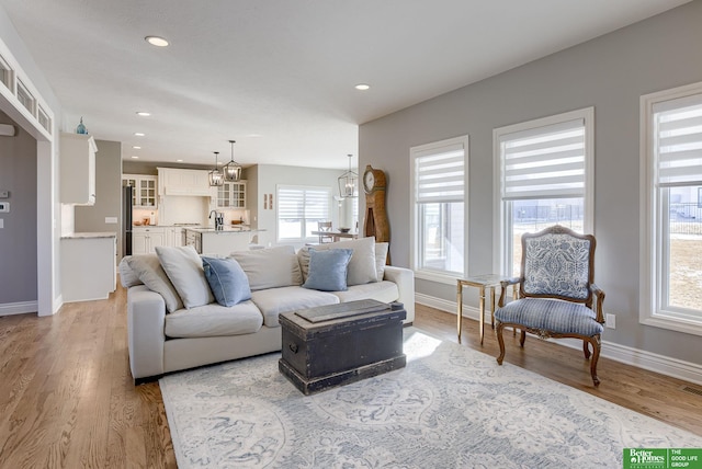 living area with recessed lighting, baseboards, and light wood finished floors