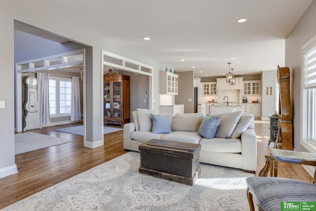 living area with a notable chandelier, recessed lighting, wood finished floors, and baseboards