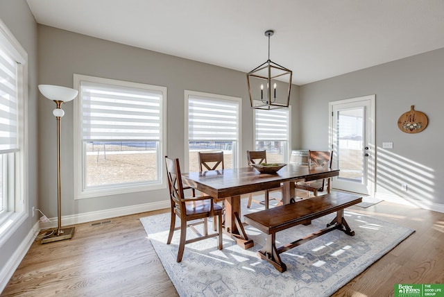 dining room featuring a chandelier, visible vents, light wood-style flooring, and baseboards