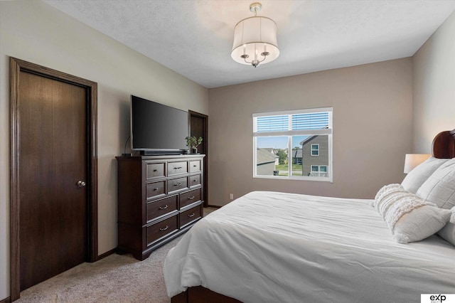 bedroom with light colored carpet, a textured ceiling, and baseboards