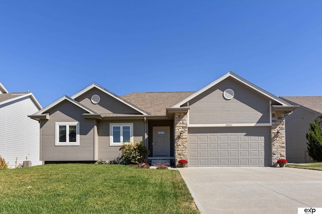 view of front facade featuring a front yard, stone siding, driveway, and an attached garage