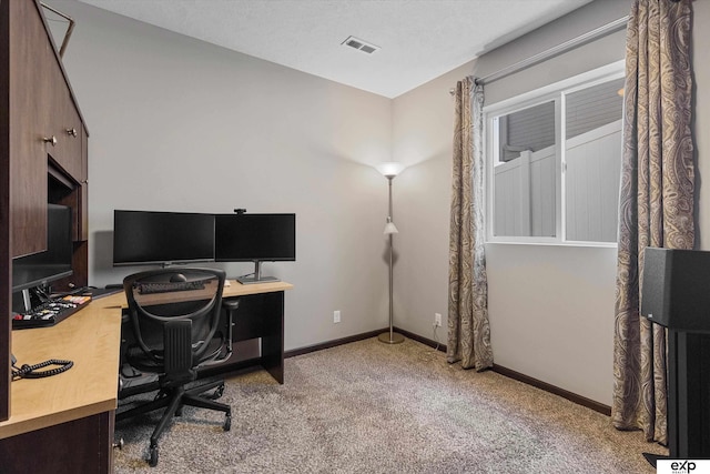 home office with light colored carpet, visible vents, a textured ceiling, and baseboards