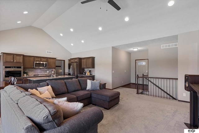 living room featuring light carpet, visible vents, high vaulted ceiling, and baseboards