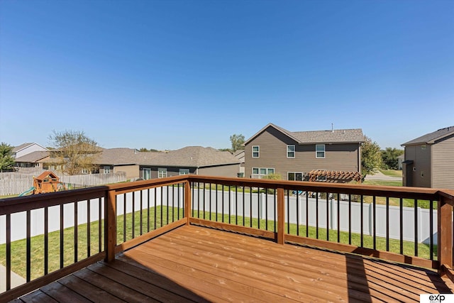 wooden deck featuring fence private yard, a residential view, a playground, and a yard