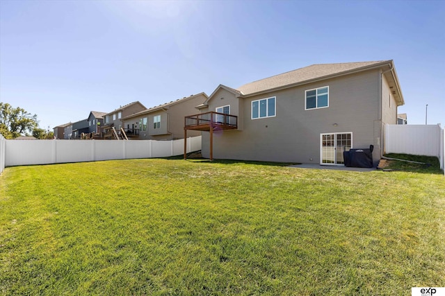 rear view of property with a balcony, a fenced backyard, and a yard