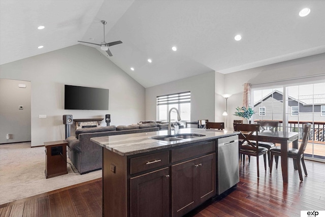 kitchen featuring a center island with sink, open floor plan, a sink, light stone countertops, and dishwasher