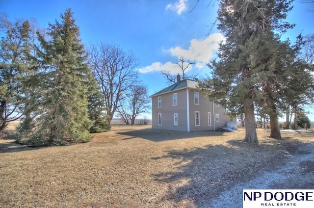 view of side of home with a chimney and a lawn