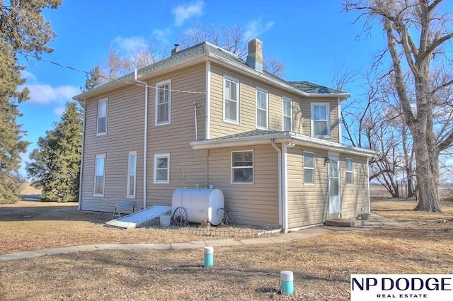 view of home's exterior with entry steps, a chimney, and heating fuel