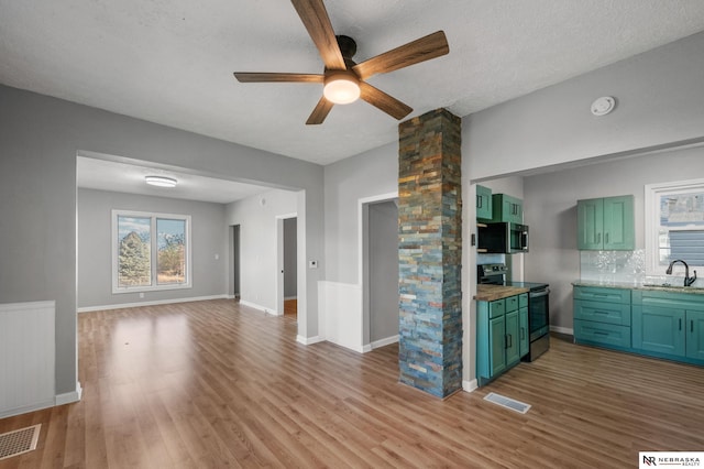 kitchen featuring appliances with stainless steel finishes, open floor plan, visible vents, and a sink