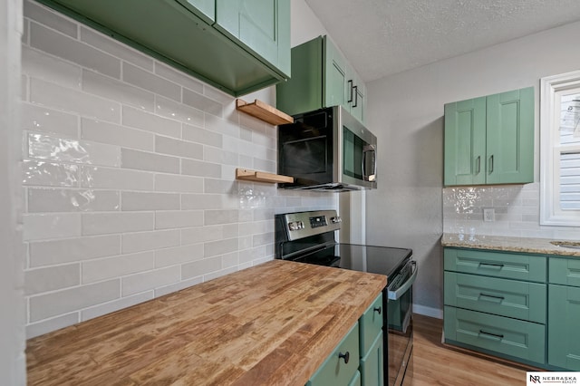 kitchen featuring open shelves, green cabinets, and stainless steel appliances