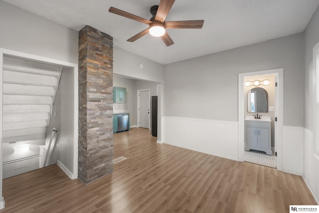 spare room featuring visible vents, a wainscoted wall, ceiling fan, wood finished floors, and a sink