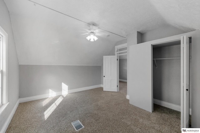 additional living space featuring carpet floors, a textured ceiling, and lofted ceiling