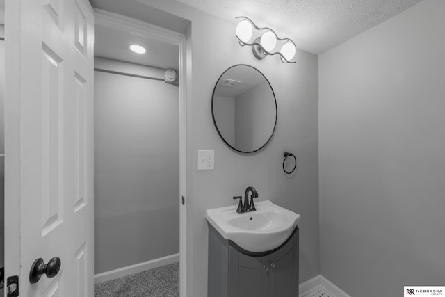 bathroom with baseboards, a textured ceiling, and vanity