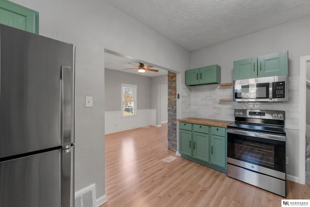 kitchen featuring visible vents, stainless steel appliances, light wood-type flooring, wooden counters, and green cabinetry