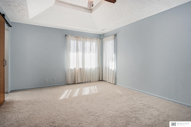 empty room with light carpet, a barn door, baseboards, a ceiling fan, and a textured ceiling