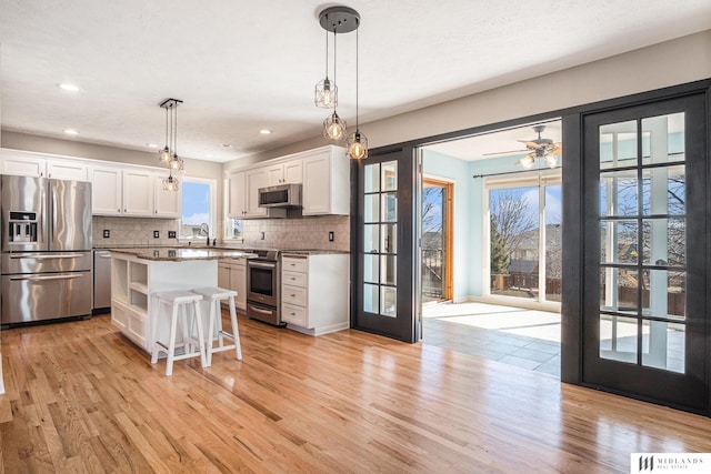 kitchen with a center island, a breakfast bar area, stainless steel appliances, and decorative light fixtures