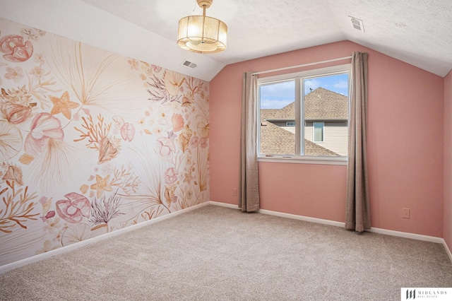 carpeted empty room featuring visible vents, vaulted ceiling, a textured ceiling, and baseboards