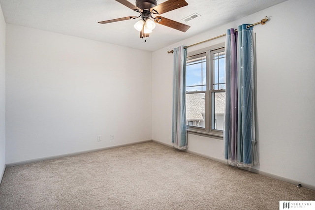 carpeted spare room featuring visible vents, ceiling fan, and baseboards