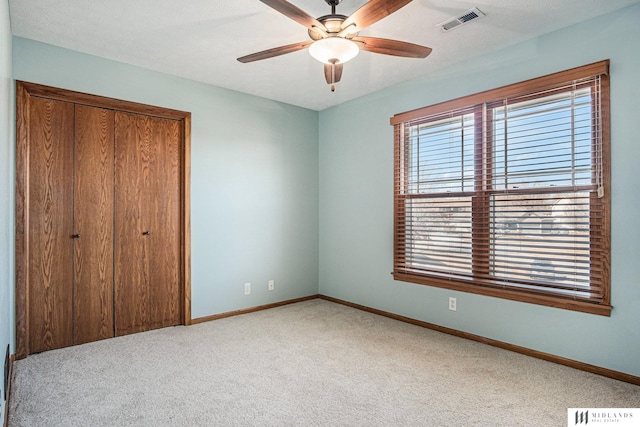 unfurnished bedroom with a closet, visible vents, light carpet, and baseboards