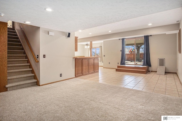 unfurnished living room featuring light carpet, light tile patterned floors, a textured ceiling, and recessed lighting