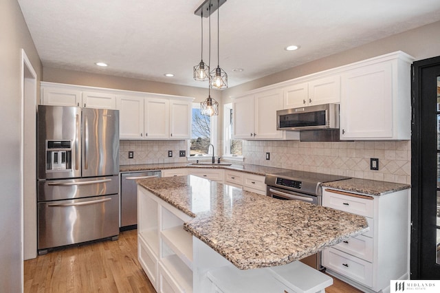 kitchen with decorative light fixtures, a center island, stainless steel appliances, white cabinetry, and open shelves