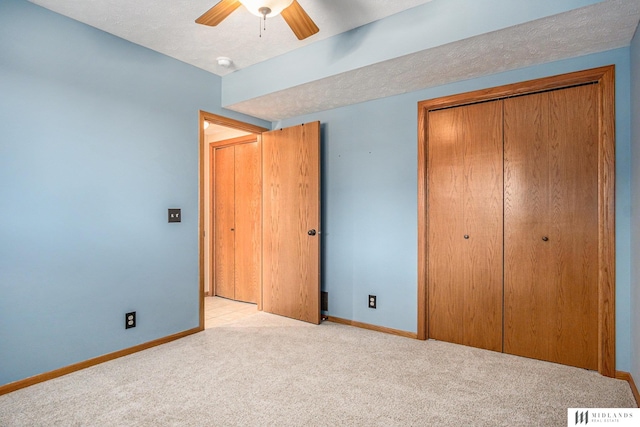 unfurnished bedroom featuring a closet, visible vents, light colored carpet, a textured ceiling, and baseboards