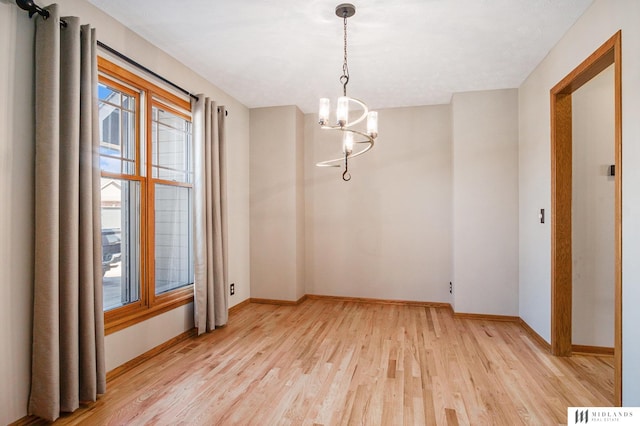 unfurnished room featuring light wood-type flooring, visible vents, baseboards, and a notable chandelier