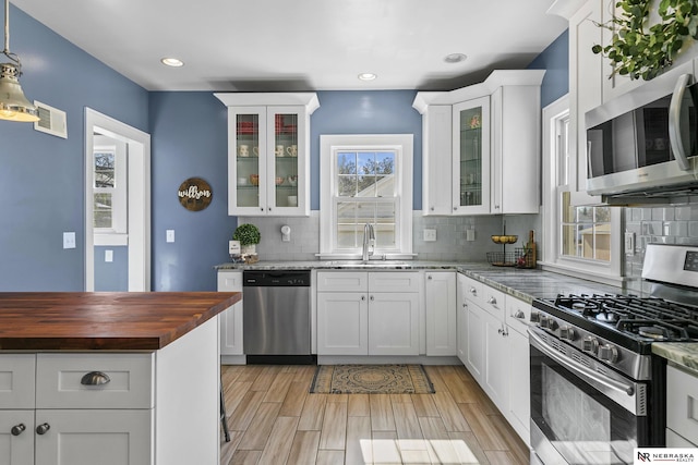 kitchen featuring stainless steel appliances, tasteful backsplash, visible vents, glass insert cabinets, and white cabinetry