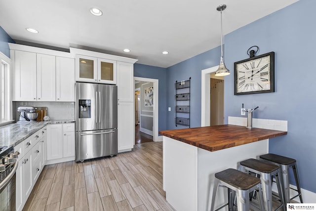 kitchen featuring appliances with stainless steel finishes, butcher block counters, glass insert cabinets, and white cabinets