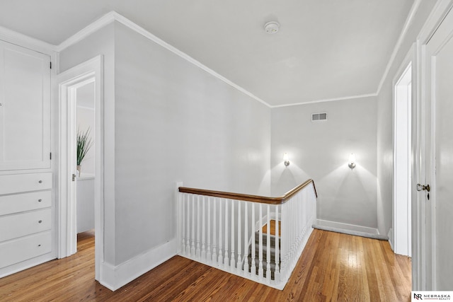 corridor featuring visible vents, crown molding, baseboards, and hardwood / wood-style flooring