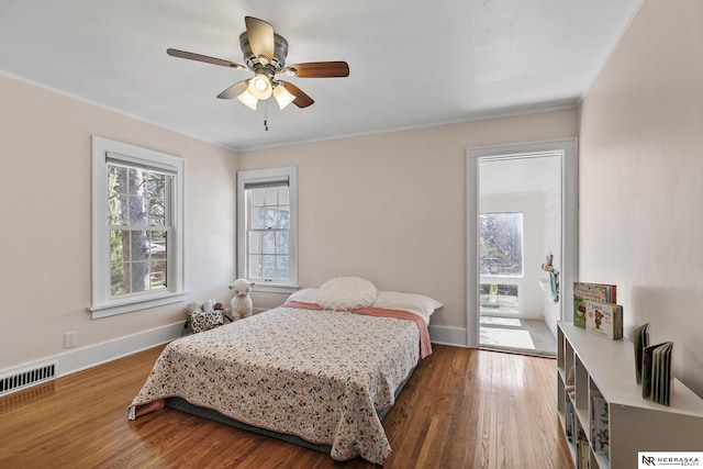 bedroom with ornamental molding, visible vents, and wood finished floors