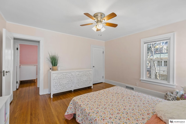 bedroom featuring light wood finished floors, baseboards, visible vents, a ceiling fan, and ornamental molding