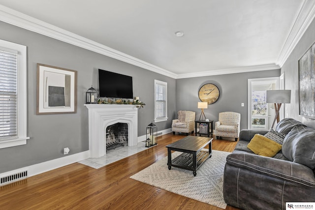 living area featuring light wood-style floors, visible vents, crown molding, and a fireplace with flush hearth