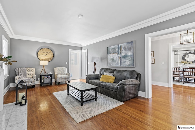 living area featuring ornamental molding, wood-type flooring, baseboards, and an inviting chandelier