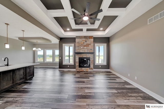 unfurnished living room with baseboards, visible vents, dark wood-style floors, a fireplace, and a sink