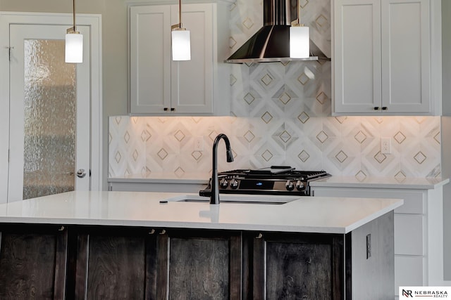 kitchen with an island with sink, light countertops, extractor fan, and pendant lighting