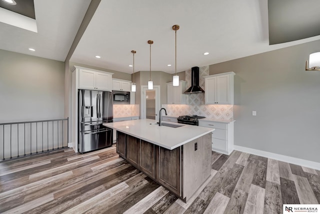 kitchen featuring stainless steel fridge with ice dispenser, wall chimney exhaust hood, a kitchen island with sink, built in microwave, and light countertops