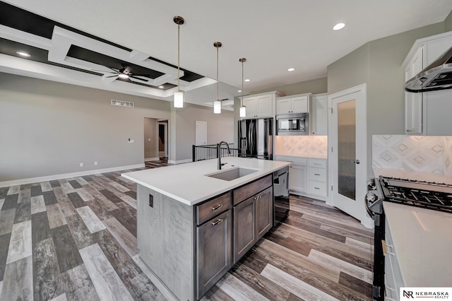 kitchen featuring light countertops, a kitchen island with sink, white cabinets, a sink, and black appliances