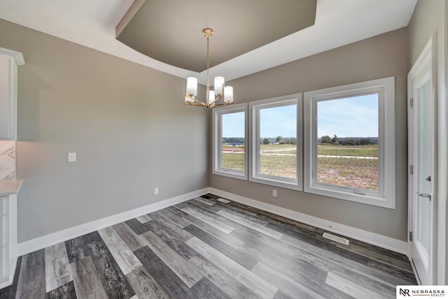 unfurnished dining area with a tray ceiling, plenty of natural light, visible vents, and baseboards