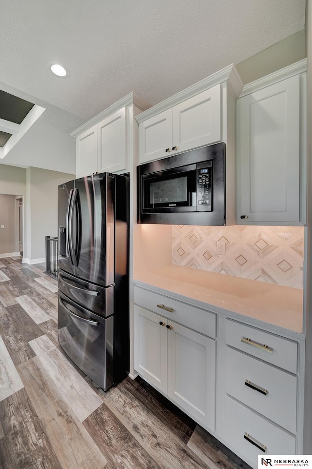 kitchen with stainless steel appliances, light wood-type flooring, white cabinetry, and backsplash