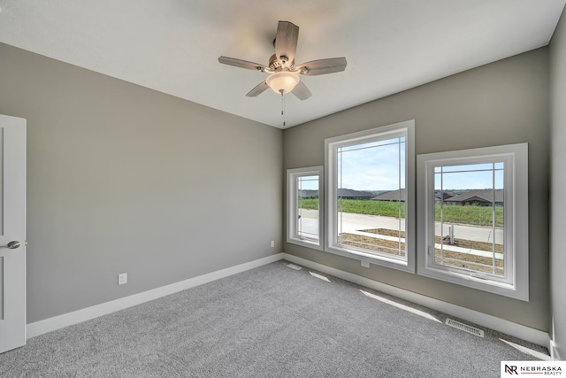 unfurnished room with a ceiling fan, carpet flooring, visible vents, and baseboards