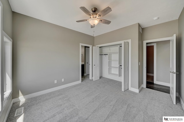 unfurnished bedroom with visible vents, a closet, light colored carpet, and baseboards