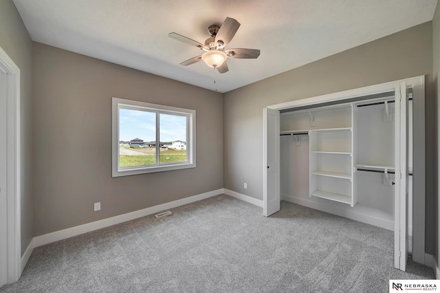 unfurnished bedroom with a closet, visible vents, light carpet, ceiling fan, and baseboards