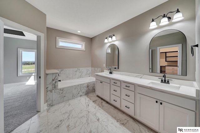 full bathroom with marble finish floor, a healthy amount of sunlight, a sink, and a bath