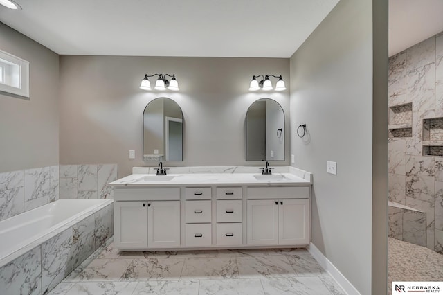 bathroom featuring marble finish floor, a sink, a tub with marble appearance, and double vanity