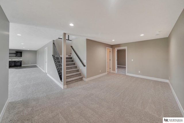 finished basement featuring stairs, recessed lighting, light colored carpet, and baseboards