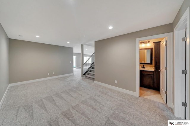 interior space with baseboards, light colored carpet, stairway, a sink, and recessed lighting