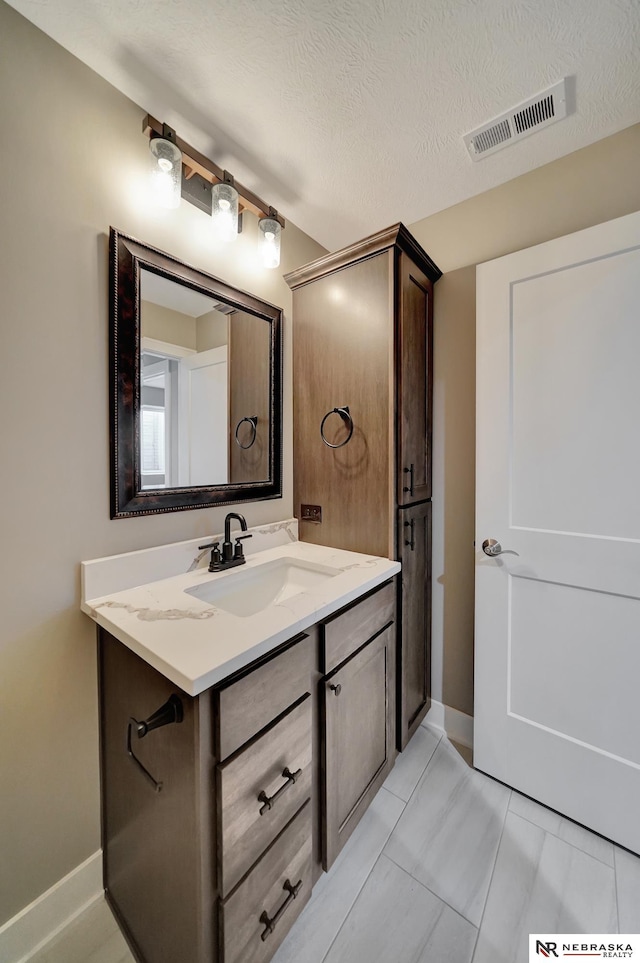 bathroom with visible vents, a textured ceiling, and vanity