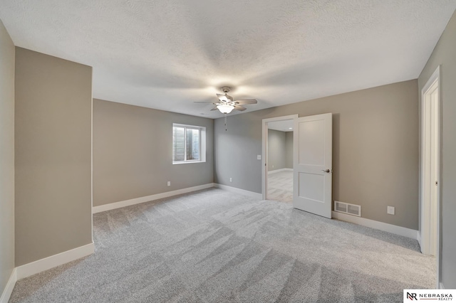 unfurnished bedroom with baseboards, a textured ceiling, visible vents, and light colored carpet